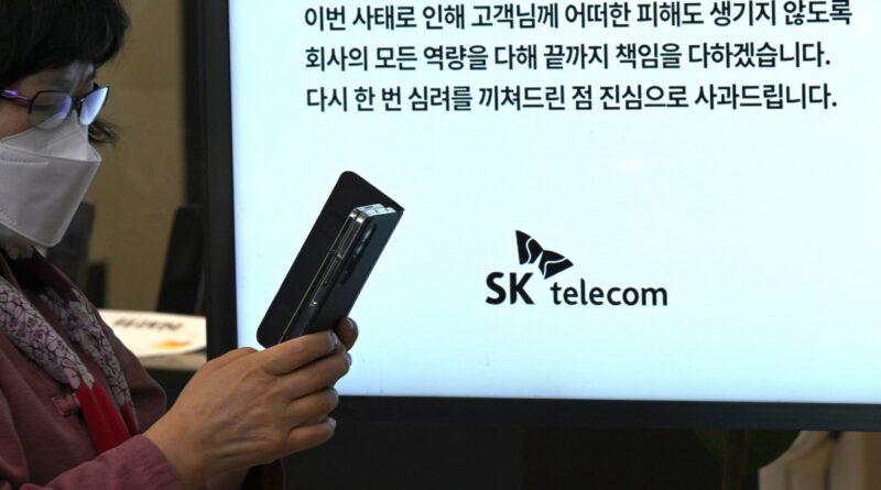 A woman uses her mobile phone while waiting to replace her USIM ship in front of an SK Telecom branch in Seoul on April 28, 2025.