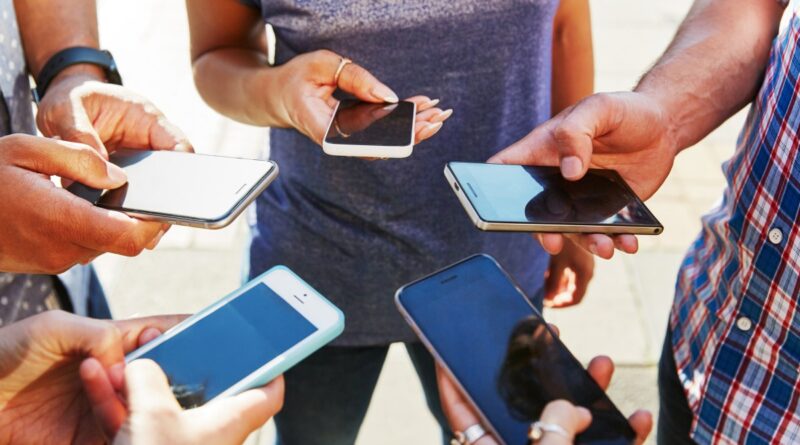 5 friends with smartphones, close up.