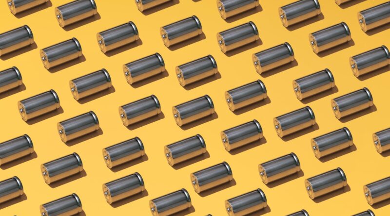 A large group of batteries laid in a pattern on a yellow background