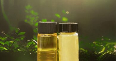 Two vials of oil sit against a leafy backdrop.