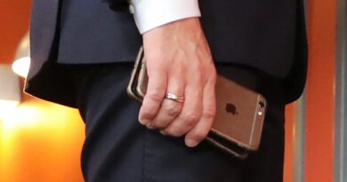 France's President Emmanuel Macron holds his mobile phones while talking with Slovakia's Prime minister during the European Social Summit in Gothenburg, Sweden