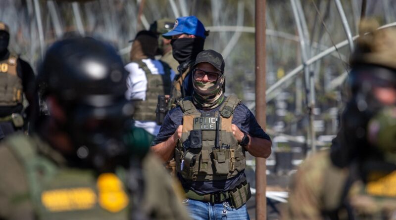 A US Immigration and Customs Enforcement agent watches as Customs and Border Protection officers hold the line against protestors who responded to a Federal Immigration raid at Glass House Farms in Camarillo, California, July 10, 2025.