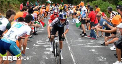 Tom Pidcock riding in the Vuelta a Espana as spectators stand on the road and encourage cyclists