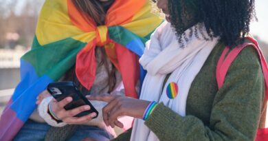 Two young women are using a smartphone while showing their support for LGBTQ+ rights