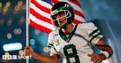Aaron Rodgers runs onto the field for his New York Jets debut carrying an American flag