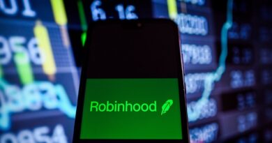 This photo illustration shows a Robinhood logo is displayed on a smartphone with stock market percentages on the background.