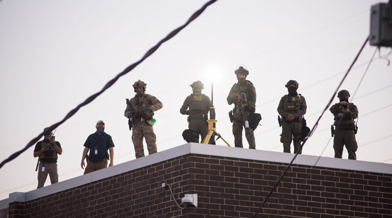 U.S. Immigration and Customs Enforcement (ICE) agents, Department of Homeland Security (DHS) personnel, and Border Patrol Commander Gregory Bovino stand together amidst a tense protest outside the ICE processing facility in Broadview, Illinois, on September 27, 2025.