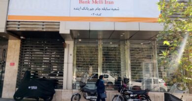 An Iranian woman walks past a branch of the state-owned Melli Bank, which absorbed the assets of the now-defunct Ayandeh Bank, with signage on its facade reading in Farsi "This former Ayandeh Bank branch is now part of Melli Bank"in the capital Tehran on October 25, 2025.