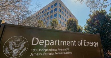 The U.S. Department of Energy building is seen behind a sign marking the location of the agency's headquarters.