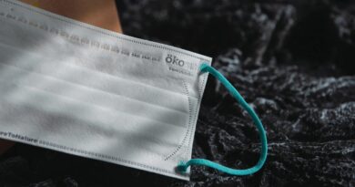A white surgical mask sits on a black rock.