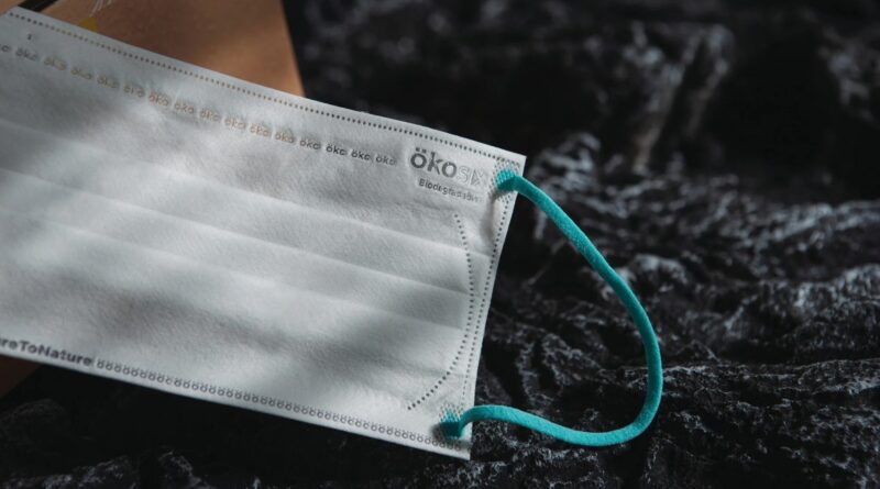 A white surgical mask sits on a black rock.