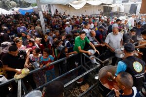 Palestinians gather to receive food from a charity kitchen, in Nuseirat, central Gaza Strip, October 7, 2025. REUTERS/Mahmoud Issa