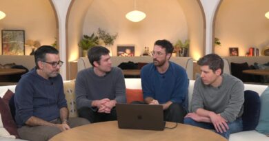 Four OpenAI employees wearing crewneck sweaters sit around a café table.