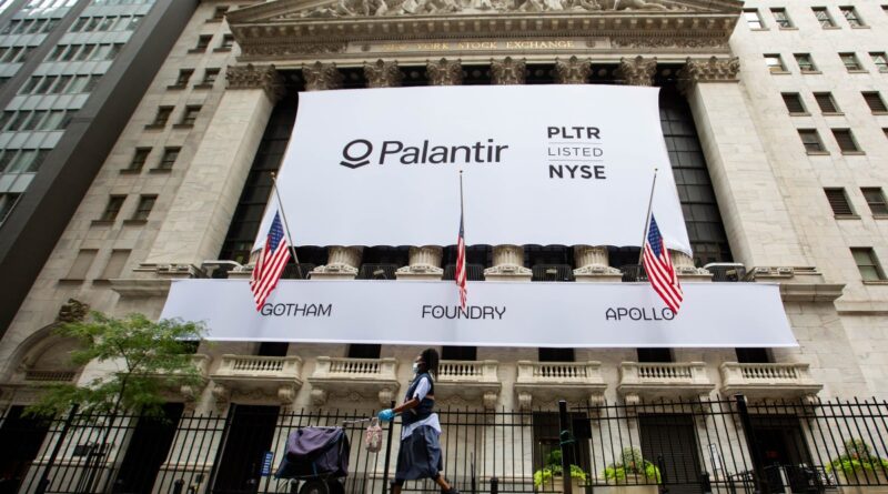 A mail carrier wearing a protective mask passes a banner displaying Palantir Technologies Inc. signage during the company's initial public offering (IPO) in front of the New York Stock Exchange (NYSE) in New York, U.S., on Wednesday, Sept. 30, 2020.