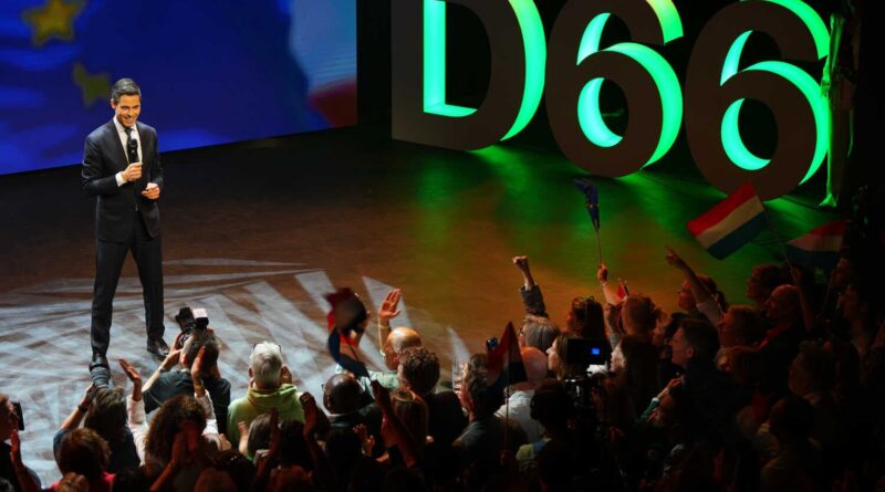 A politician speaking next to the illuminated letters “D66” and a projection featuring an E.U. flag.