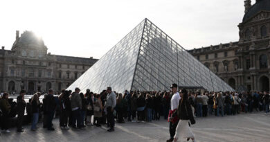Lines of people outside the glass pyramid at the Louvre Museum in Paris.