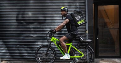 Side shot of food delivery worker on Whizz e-bike on NYC street in front of street mural