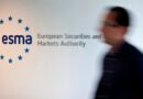 A blurred person walks past a wall sign for the European Securities and Markets Authority (ESMA) at its headquarters.