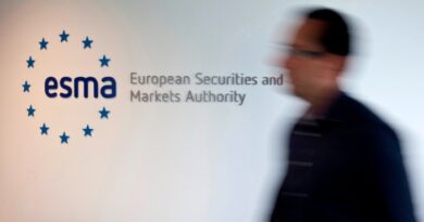 A blurred person walks past a wall sign for the European Securities and Markets Authority (ESMA) at its headquarters.