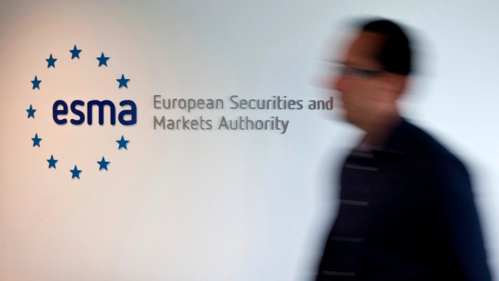 A blurred person walks past a wall sign for the European Securities and Markets Authority (ESMA) at its headquarters.