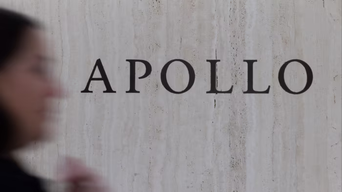 Apollo Global Management signage on a marble wall, with a blurred person passing in the foreground.