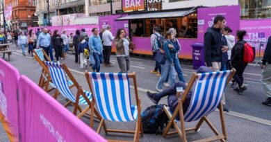 Deckchairs with blue and white stripes are set up on the street as people walk past during the Oxford Street pedestrianisation event.