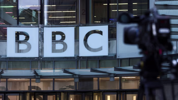 The BBC logo displayed on the exterior of BBC Broadcasting House, with a video camera visible in the foreground.