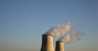 Cooling towers for a nuclear reactor stand against a blue sky.