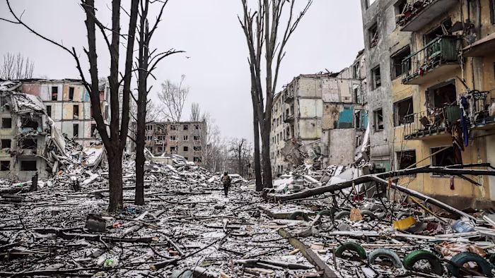A Ukrainian serviceman walks through rubble between destroyed residential buildings and leafless trees in Kostyantynivka.