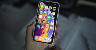 a person holding new iPhone XS smartphone in their hand over a notepad.