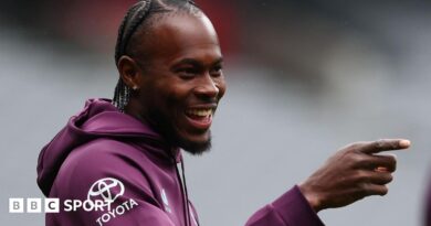 Jofra Archer smiles and points with his right hand