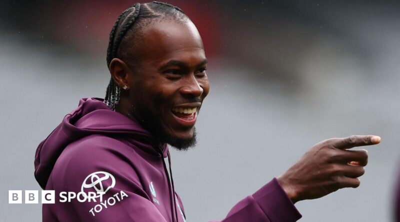 Jofra Archer smiles and points with his right hand