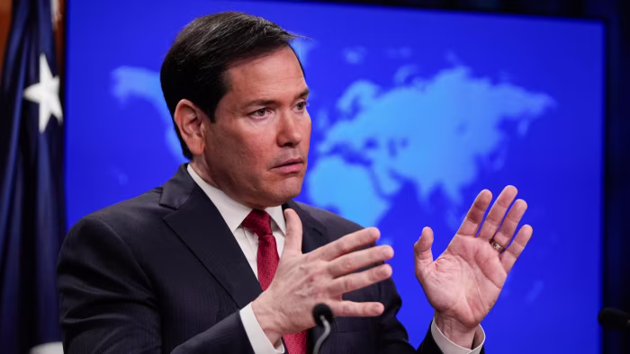 Marco Rubio gestures with both hands while speaking at a podium during a news conference.