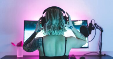 Image of a woman putting on headphones in front of a computer screen and microphone.