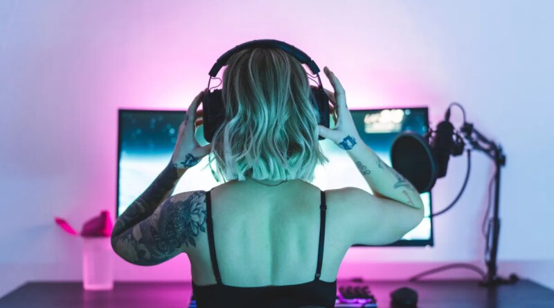 Image of a woman putting on headphones in front of a computer screen and microphone.