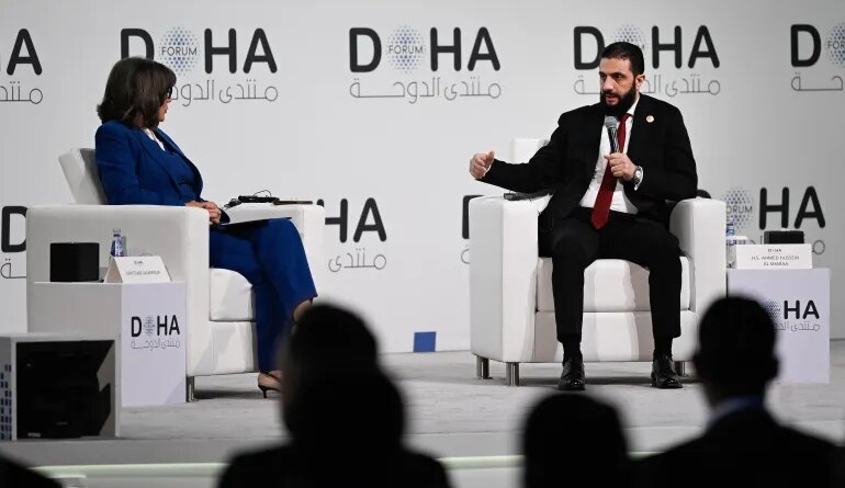 Syrian President Ahmed al-Sharaa (R) speaks during the opening day of the Doha Forum, an annual diplomatic conference, in Doha on December 6, 2025.
