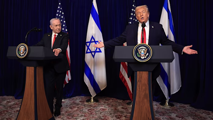Benjamin Netanyahu, left, and Donald Trump stand at podiums during a press conference, with US and Israeli flags behind them.