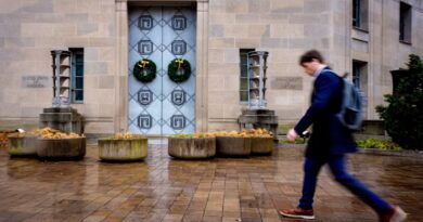 The entrance of the Robert F Kennedy Department of Justice Building with two wreaths on the doors and a person walking past.