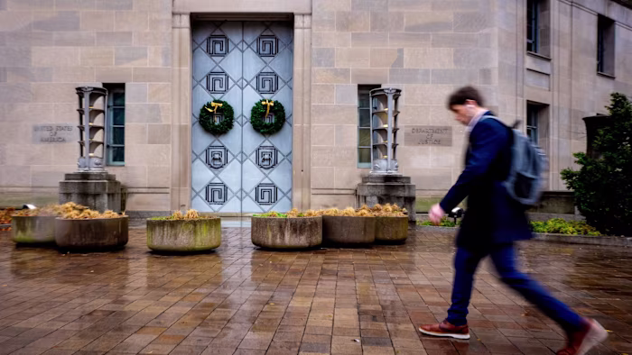 The entrance of the Robert F Kennedy Department of Justice Building with two wreaths on the doors and a person walking past.