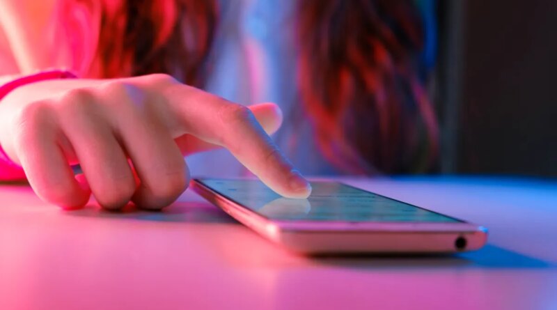 person touching a smartphone laying on a table.