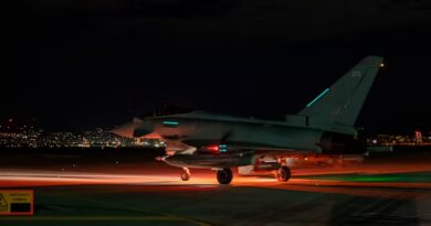 Royal Air Force Typhoon aircraft on a runway at night, illuminated by red and green lights, preparing for take-off.