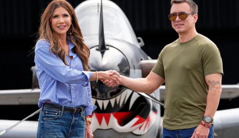 Kristi Noem and Daniel Noboa shake hands in front of a fighter jet