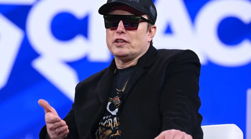 Elon Musk on stage at CPAC in Maryland with sunglasses on and a MAGA hat