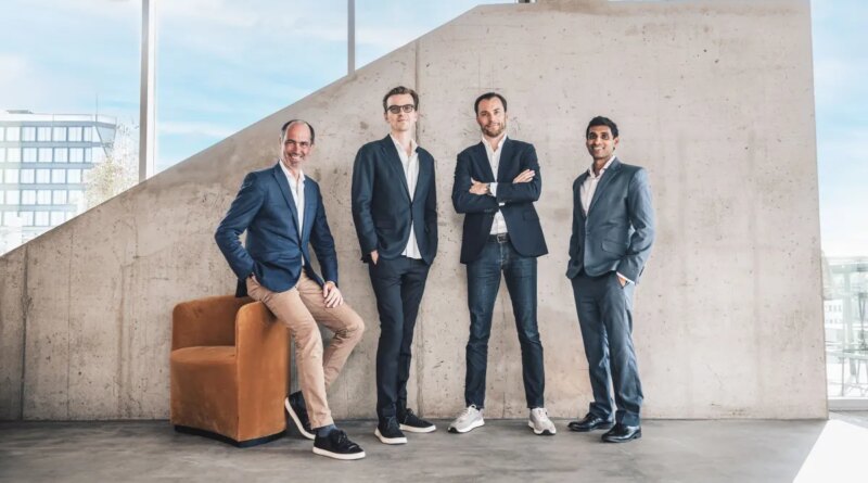 Four men standing in front of a concrete wall.