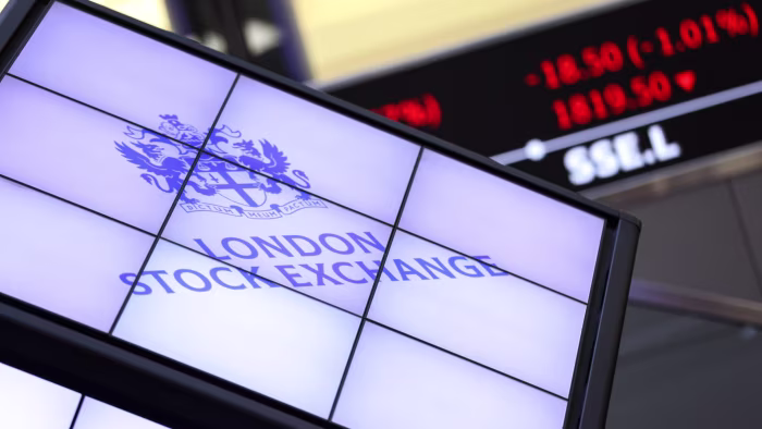 London Stock Exchange logo on a digital display with a stock ticker showing falling prices in the background.