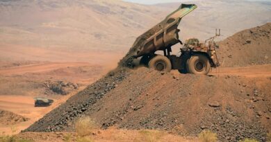 An autonomous haul truck unloads a pile of rock at a mining site, with another haul truck visible in the background.