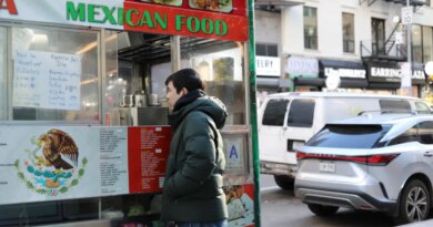 A man places an order at a Mexican food cart.