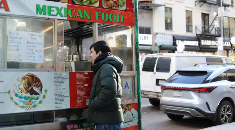 A man places an order at a Mexican food cart.
