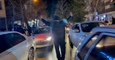 A protester flashes victory signs as traffic slows during demonstrations in Hamedan, Iran, on January 1, 2026.