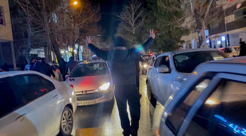 A protester flashes victory signs as traffic slows during demonstrations in Hamedan, Iran, on January 1, 2026.